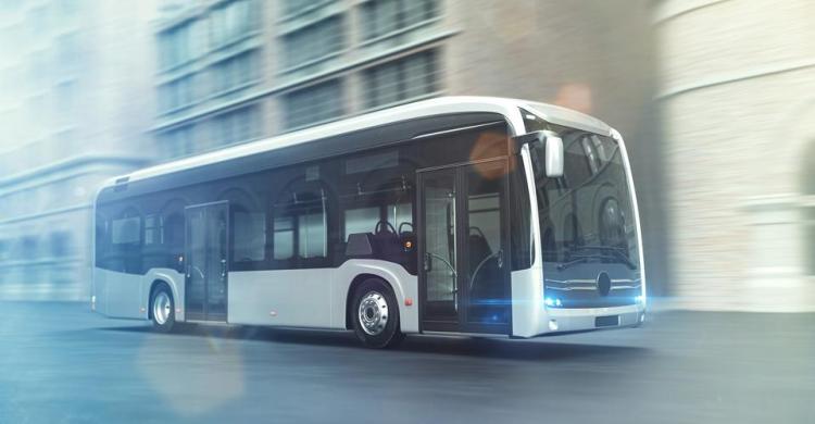 Ein moderner Elektrobus in stilvollem, futuristischem Design fährt durch eine städtische Umgebung mit historischen Gebäuden im Hintergrund. Der Bus hat ein glänzendes Gehäuse mit großen Fenstern und leuchtenden Scheinwerfern, was ein Gefühl von Innovation und Nachhaltigkeit vermittelt.