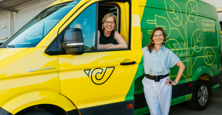 Leonore Gewessler sitzt in einem Post-Fahrzeug, während Karin Tausz an der offnen Fahrertür lehnt