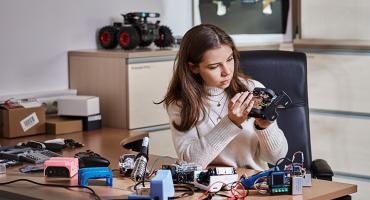 Mädchen mit Elektronik-Bauteilen an einem Schreibtisch