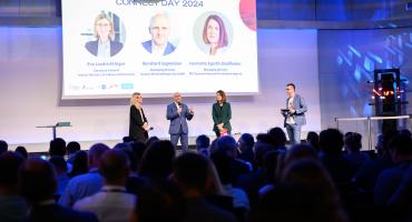 Eva Landrichtinger, Bernhard Sagmeister und Henrietta Egerth stehen auf einer Bühne und begrüßen zum Connect Day 2024