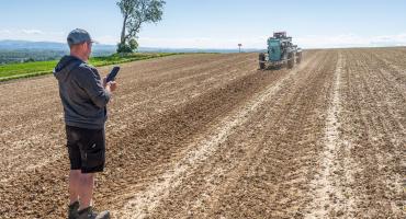 Ein Mann steht auf einem Feld und bedient einen Roboter