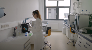 Eine Frau steht in einem Labor und arbeitet mit einer Pipette