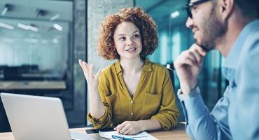 Eine Frau und ein Mann sitzen in einem Büro vor einem Laptop. Foto: iStock